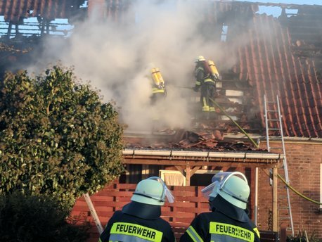 Ein Atemschutztrupp öffnet unter PA das Dach eines brennenden Gebäudes